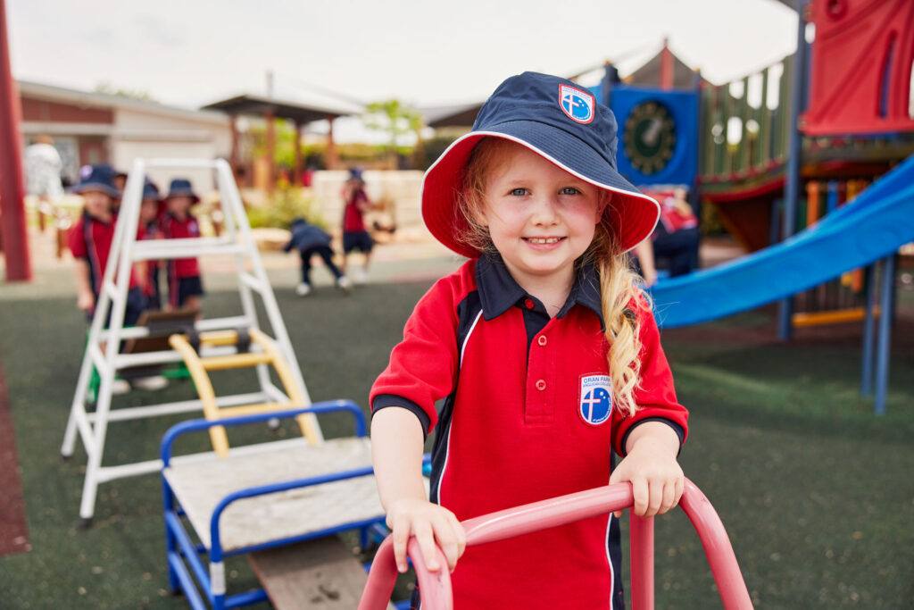 Prep student on play equipment smiling at camera